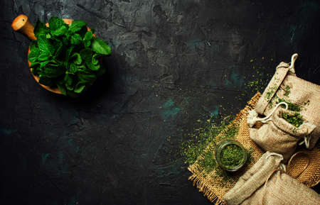 Dried peppermint in a glass jar and a bunch of fresh mint, medicine herb on black background, top viewの写真素材