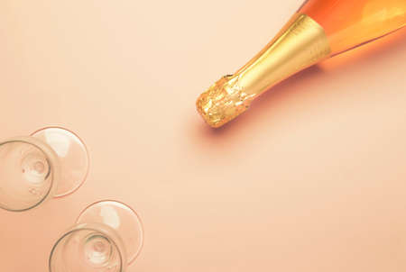 Bottle with pink sparkling wine or rose champagne and glasses, trendy pink background with place for text, holiday or date concept, flat lay, top viewの写真素材