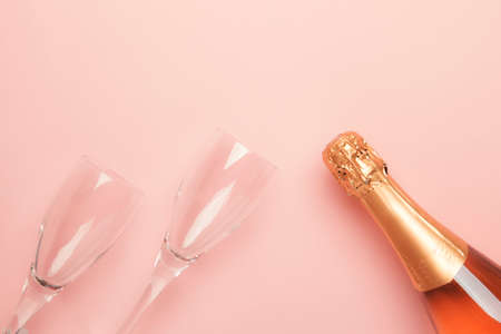 Bottle with pink sparkling wine or rose champagne and glasses, trendy pink background with place for text, holiday or date concept, flat lay, top viewの写真素材