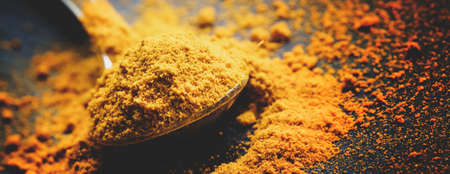 Ground turmeric or curcuma, black background, close-up shot, selective focus and toned image