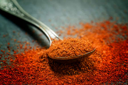 Ground sweet red paprika in a spoon on a dark background, selective focus, shallow depth of field