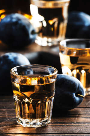 Slivovica - plum brandy or plum vodka, Balkan hard liquor, strong drink in shot glasses on old wooden table, copy spaceの写真素材