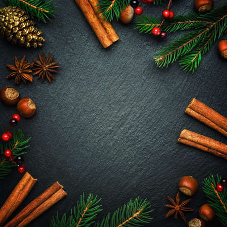 Christmas or New Year dark background, frame, template, with festive decorations, winter spices and Christmas decorations, nuts and fir branches, top viewの写真素材