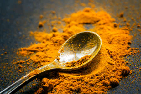 Ground turmeric or curcuma, black background, close-up shot, selective focus