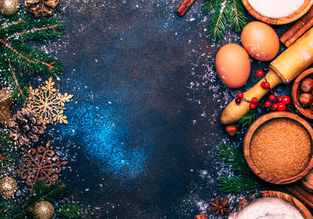 Christmas composition with ingredients for baking or with golden snowflakes, Christmas balls, green fir branches, pine cones, on blue brown background, frame, top viewの写真素材