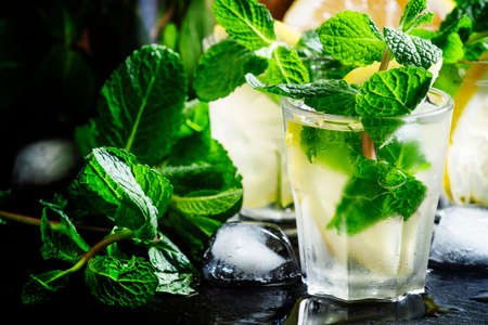 Alcoholic cocktail with vodka and ice mint tea, black background, selective focus