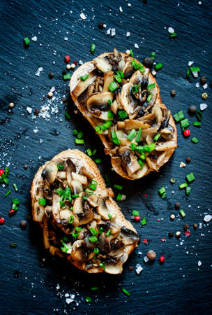 Tasty sandwiches with grilled mushrooms and green onions with bran bread on a dark background, top viewの写真素材
