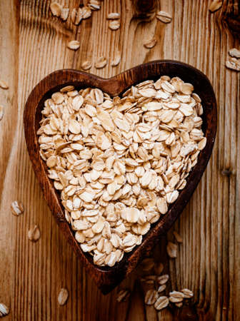 Oat flakes in a wooden bowl in the shape of a heart, top viewの写真素材