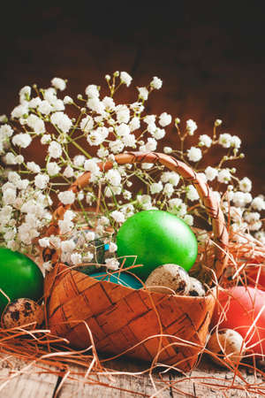 Multi-colored Easter eggs in a wicker basket in a rustic style, selective focus