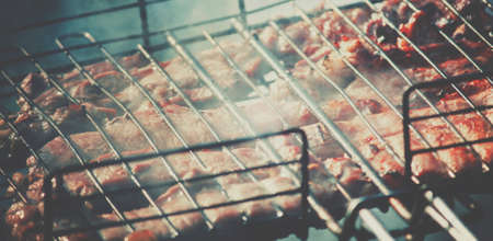 Meat on the grill cooking on the coals, preparation shish kebab or barbecue, shallow depth of field and toned imageの写真素材