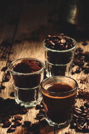 Black espresso coffee and ingredients for cooking: roasted coffee beans, ground coffee, Turkish coffee maker, vintage wooden background, selective focusの写真素材