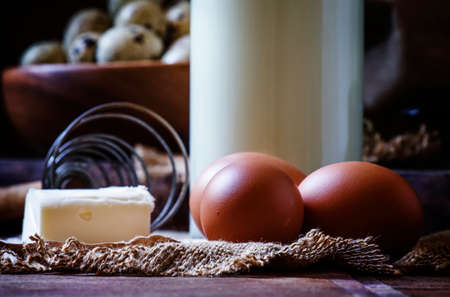 Fresh organic eggs, milk and butter, still life in rustic style, vintage wooden background, selective focusの写真素材