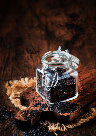 Black quinoa seeds in glass jar, vintage kitchen table background, selective focusの写真素材