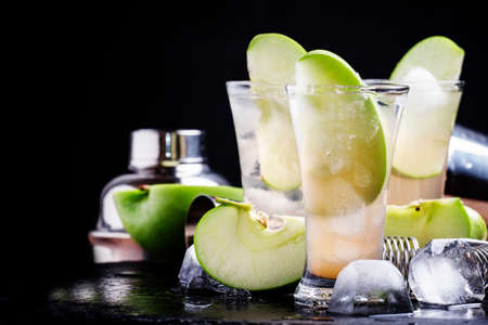 Apple cocktail with rum and juice. Bar metal tools. Black stone background, selective focusの写真素材