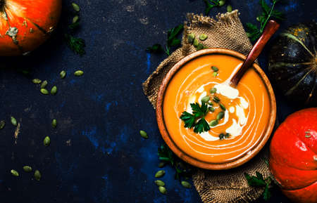 Cream pumpkin soup in a wooden bowl, rustic style, top view
