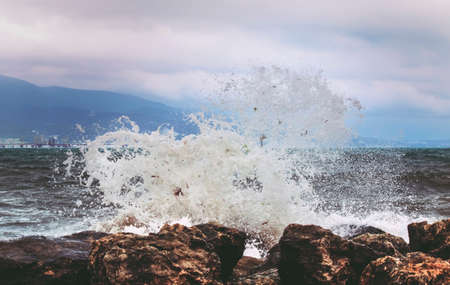 Waves breaking on big rocks, storm on the black sea in cloudy day