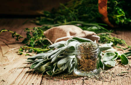 Dried sage in a glass jar, fresh sage on the vintage wooden table, preparation of medicinal herbs drying, selective focusの写真素材