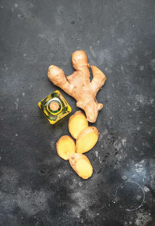Healing Ginger oil and fresh ginger root, gray kitchen table, copy space, top view