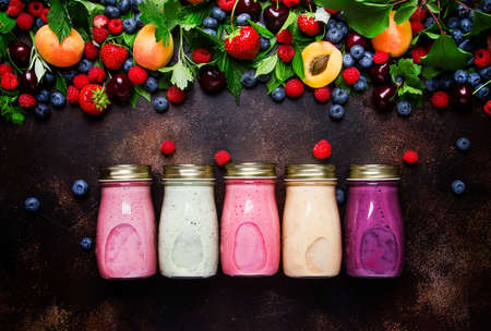 Healthy and useful colorful berry smoothies with yogurt, fresh fruit and raw berries on brown background, top viewの写真素材