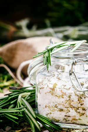 Sea salt with dried rosemary in a glass jar, vintage wooden background, selective focusの写真素材