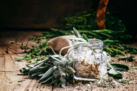 Sea salt, milled with sage in a glass jar, fresh herbs, vintage wooden background, selective focusの写真素材
