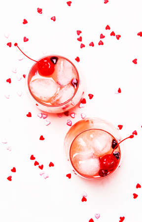 Pink alcoholic cocktail for Valentines day, two glasses, white background with sweet hearts, top viewの写真素材
