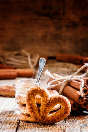 Pretzels with ground cinnamon, cinnamon sticks, brown cane sugar on the old wooden background, selective focusの写真素材