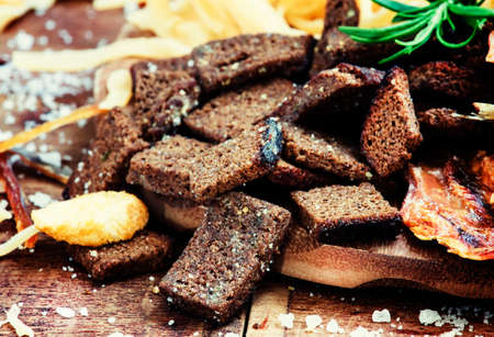 Dried crust from black rye bread with salt and spices, beer snacks, dark background, selective focusの写真素材