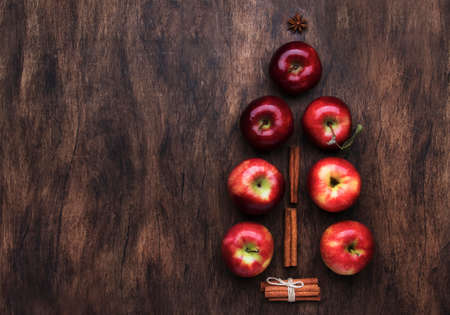 Creative Christmas tree made from red apples, cinnamon and anise star on wooden brown backgroundの写真素材