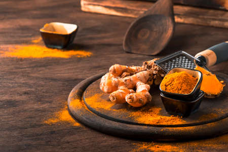 Turmeric powder and fresh turmeric on wooden backgroundの写真素材