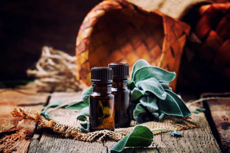 Essential sage oil in brown bottle on the vintage wooden blackground, rustic style, selective focusの写真素材