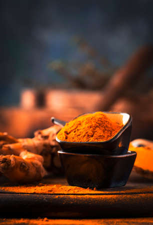 Turmeric powder and fresh turmeric on wooden background