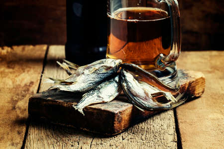 Russian tradition: dried roach and beer on vintage wooden background, selective focus
