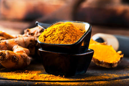 Turmeric powder and fresh turmeric on wooden background with copy spaceの写真素材