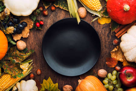 Thanksgiving dinner place setting. Autumn fruit, pumpkins, nuts, fallen leaves with plate and cutlery. Thanksgiving autumn backgroundの写真素材