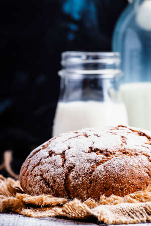 Fresh bread and cows milk in bottles, selective focus