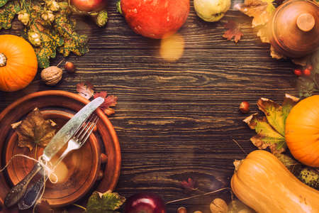 Thanksgiving dinner place setting. Autumn fruit, pumpkins, nuts, fallen leaves with plate and cutlery. Thanksgiving autumn backgroundの写真素材