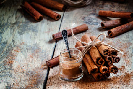 Ground cinnamon, cinnamon sticks, tied with jute rope on old wooden background in rustic style, selective focusの写真素材
