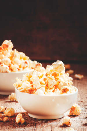 Sweet popcorn in white bowls, vintage wooden background, selective focusの写真素材