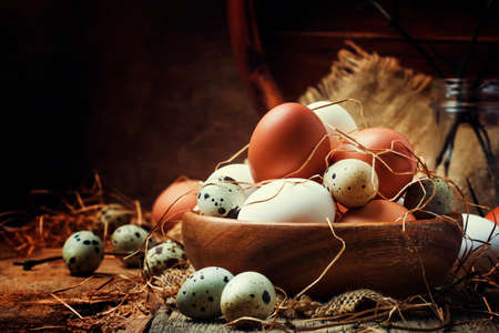 Easter composition with colorful chicken and quail eggs in rustic style, vintage wooden background,...
