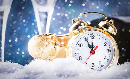 Christmas or New Year background with golden clock in snowdrifts, champagne bottle and glasses on...