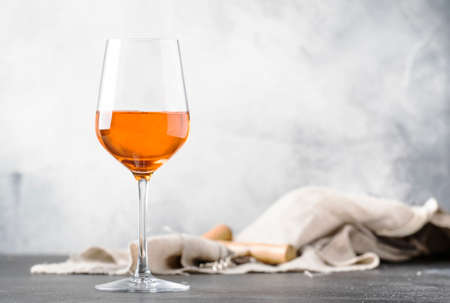 Orange wine in big wine glass, fashionable modern drink, gray counter background, copy space, selective focusの写真素材