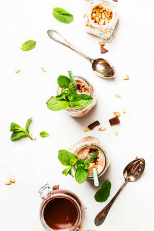 Chocolate milkshake or milk cocktail with topping, green mint and cedar nuts, white kitchen table, copy space, top viewの写真素材