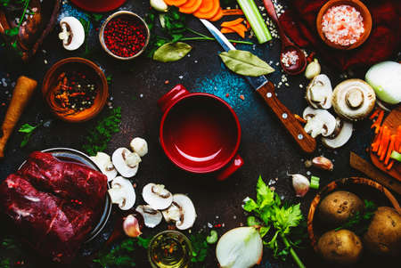 Fresh organic vegetables, ingredients, spices and meat for cooking soup on vintage kitchen table background with rustic wooden cutting board. Top view, place for text. Healthy cooking and eating conceptの写真素材