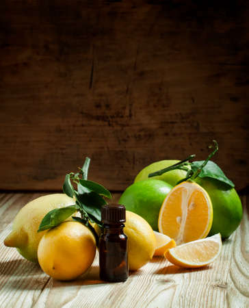 Essential oil of lemon and fresh lemons on the old wooden background, selective focusの写真素材