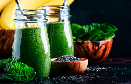 Healthy detox green smoothies with spinach, banana and chia seeds, brown background, selective focusの写真素材