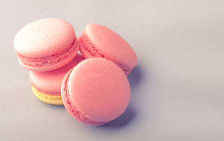 Pink yellow macaroons cakes on gray blue table background, place for text, trendy minimalism style,...