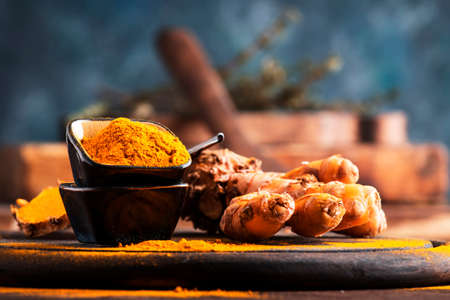 Turmeric powder and fresh turmeric on wooden background with copy spaceの写真素材