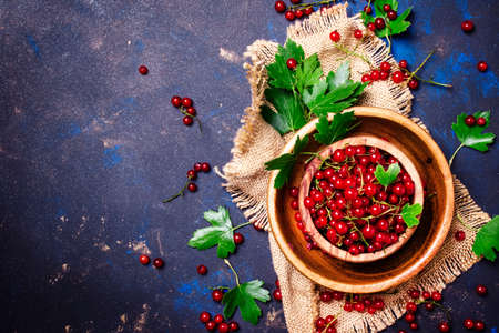 Red currant in a bowl on a canvas napkin, rustic style, food background, top view