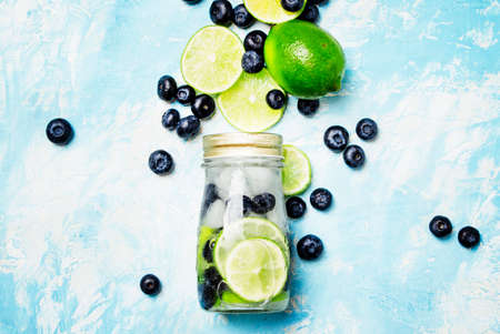 Summer refreshing beverage with blueberry, lime and ice in glass bottle, top viewの写真素材